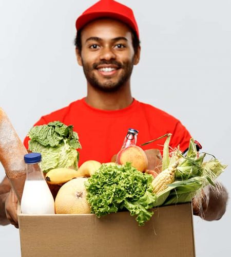Delivery Concept - Handsome African American delivery man carrying package box of grocery food and drink from store. Isolated on Grey studio Background. Copy Space.